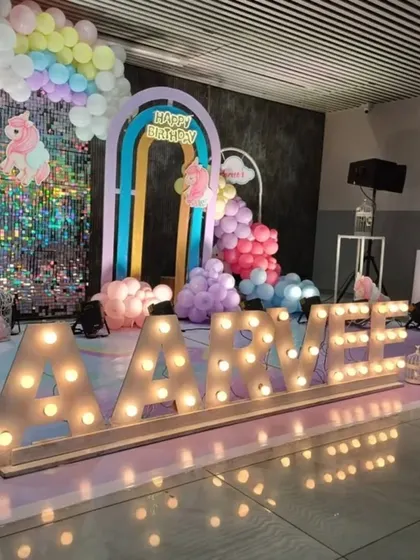 A vibrant unicorn-themed first birthday for Aarvee, featuring large marquee letters, a rainbow arch, and a sparkling sequin wall for extra magic.