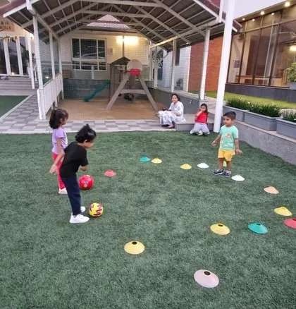 Kids practice their dribbling skills around colorful markers on a beautiful turf field. The well-maintained environment adds to the professional quality of our coaching sessions.