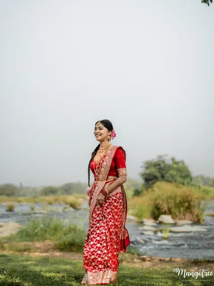 A wide shot capturing the bride in the serene landscape. Her traditional look stands out, creating a memorable and unique bridal portrait.