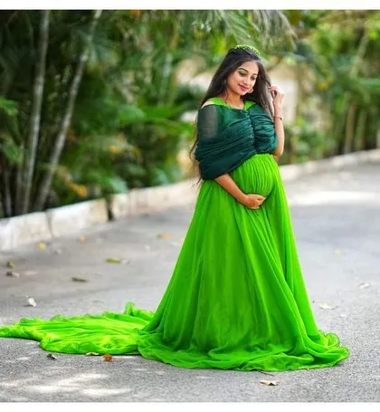 A beautiful shot of an expecting mother in a green trail gown. The long, flowing fabric adds a touch of magic to maternity photos.