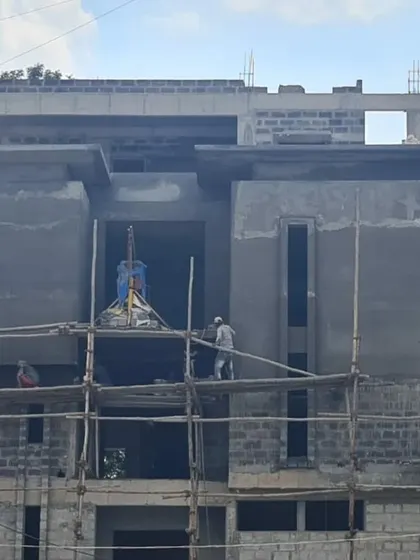A closer view of workers on the scaffolding, applying plaster to the exterior walls. This stage is critical for achieving a smooth and durable finish.