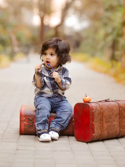 This little traveler, sitting on his suitcases, looks ready for an adventure in this creative pre-birthday portrait.