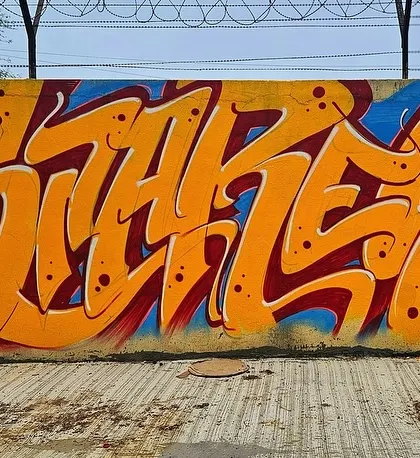 This piece features clean, interconnected letters in orange and red, showcasing a more readable but still stylized form of graffiti.