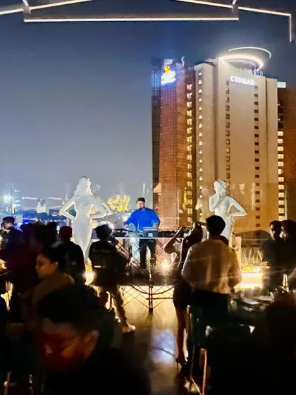 Another shot of me DJing against the stunning backdrop of the Conrad hotel from a rooftop venue.