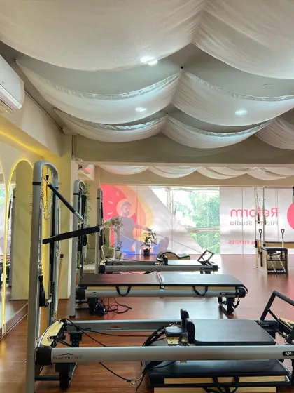 The studio is lined with reformers, ready for our small group classes. The soft, draped ceiling and large windows create a bright and airy atmosphere for your workout.