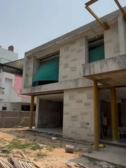 An under-construction photo of the Jammu residence. This image shows the concrete structure and the application of the stone cladding, offering a glimpse into the building process.
