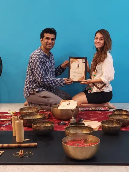 Another proud graduate of our Sound Healing Teacher Training, holding her certificate amidst the tools of her new craft.