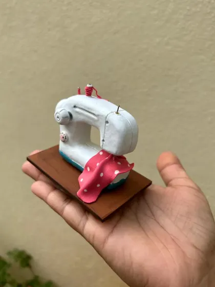 Holding the custom sewing machine miniature. It's small enough to fit in your palm but carries a big, personal message.
