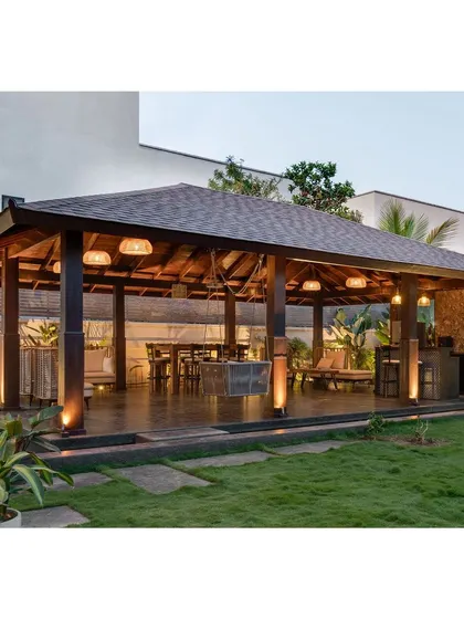 The pavilion at dusk, with warm lighting creating an inviting ambiance. It’s a versatile space that connects the home to its lush green surroundings.