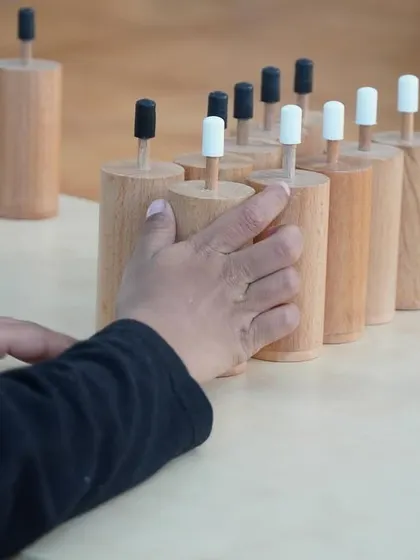 Working with the sound cylinders, a child pairs matching sounds. This activity isolates and refines the auditory sense, an important skill for developing phonemic awareness for reading.
