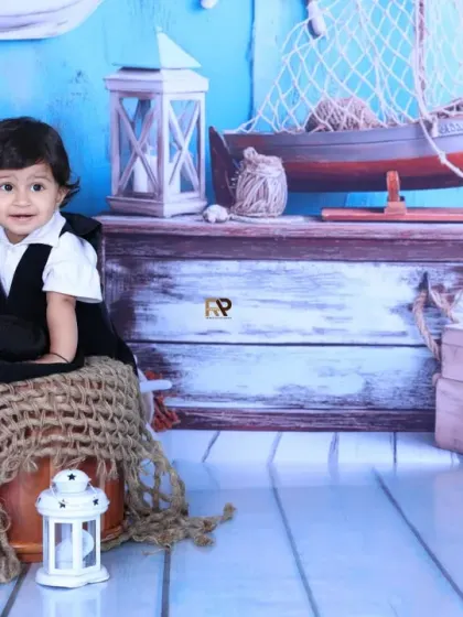 A baby sailor sits on a burlap-covered stool, ready to set sail on an adventure. The blue wooden backdrop and nautical props create a beautiful and cohesive scene.