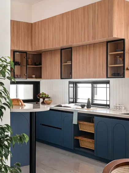 Another view of the blue and wood kitchen, showing the open shelving and the practical storage baskets integrated into the design.
