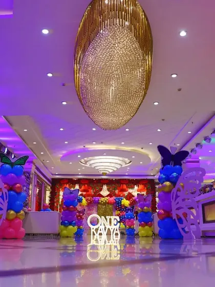 Another perspective of the banquet hall for Kavya's party, showing the entrance walkway decorated with butterfly-themed balloon pillars.