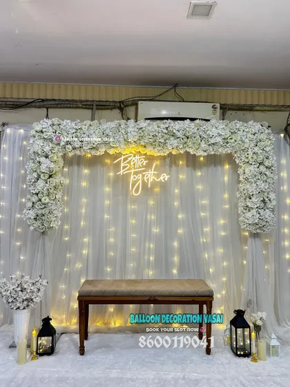 An all-white theme is timeless and elegant. Here, we used a dense white floral arch over a fairy light curtain and a "Better Together" neon sign for a dreamy engagement stage.