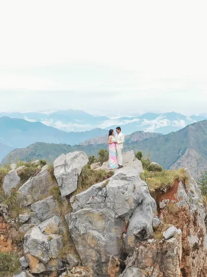 A couple stands together on a rocky peak, framed by the vast, layered ranges of the Himalayas. This is what a fairytale shoot in the mountains looks like, capturing both the scale of nature and the intimacy of the moment.