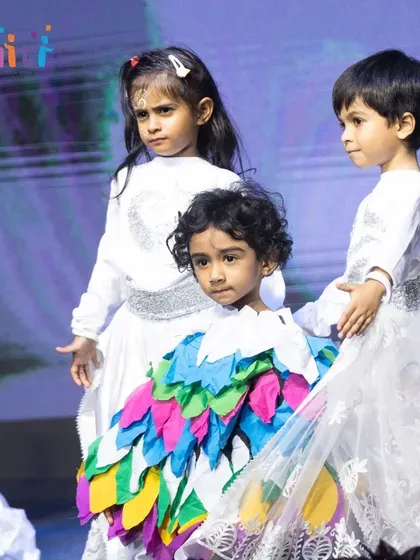 A child in a multi-colored feather costume stands among the "wind" dancers, representing the birds of the air.