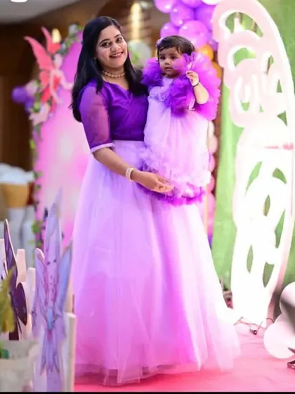 Another photo of the butterfly-themed twinning set. The mother's outfit has a sheer organza top over a lavender skirt, coordinating with her daughter's frilly frock.