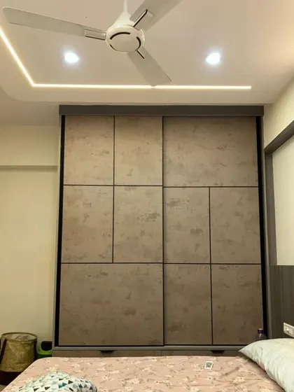 This wardrobe in a dark beige stone-finish laminate has a sophisticated and earthy feel. The sliding doors with a geometric pattern are perfect for saving space in a compact bedroom.