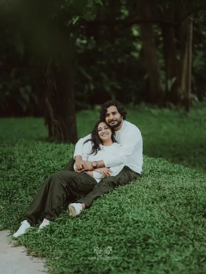 The couple embracing on a grassy hill, a sweet and romantic portrait in a natural setting.