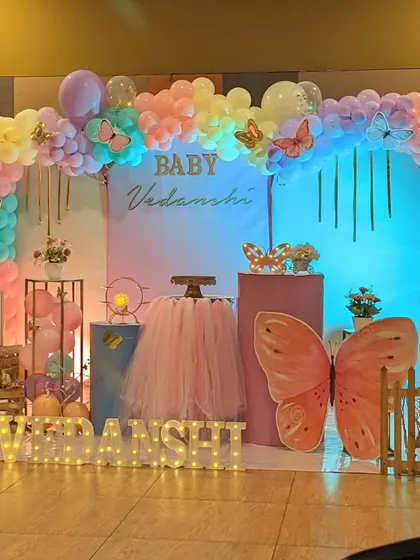 This pastel rainbow butterfly theme is perfect for a first birthday. The decor features a gentle arch of balloons, large butterfly props, and a tutu-draped table for the cake.