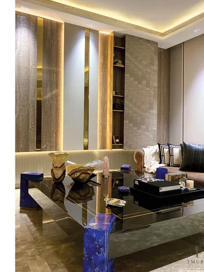 A statement coffee table with a glossy black top and striking blue lapis lazuli legs anchors this living room. It is a prime example of our in-house capability to create bespoke furniture that is both art and function.