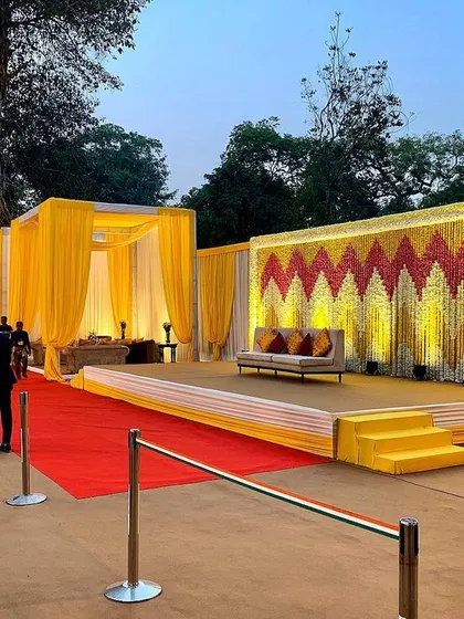 A grand stage setup for a daytime event. The backdrop combines a traditional floral pattern in red and yellow with a modern, clean stage design, showcasing my ability to blend different styles.