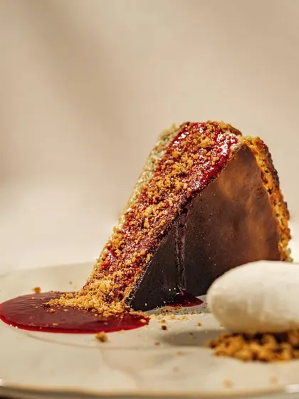 A perfectly plated slice of burnt Basque cheesecake with a side of ice cream and berry coulis. The clean, bright styling makes this dessert look both elegant and delicious.