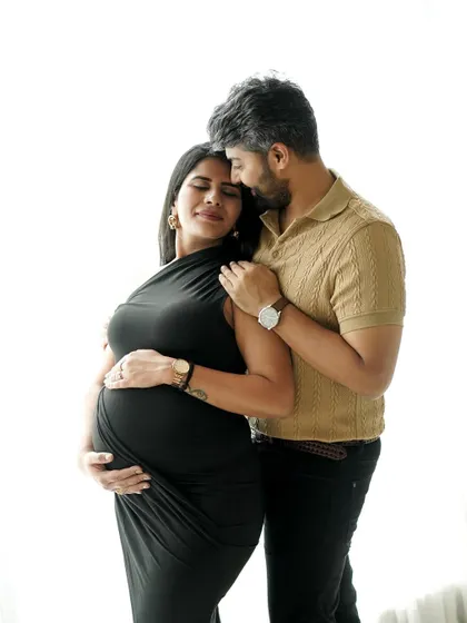 A beautiful, intimate pose against a clean, bright background, highlighting the couple's bond and the expecting mother's glow.