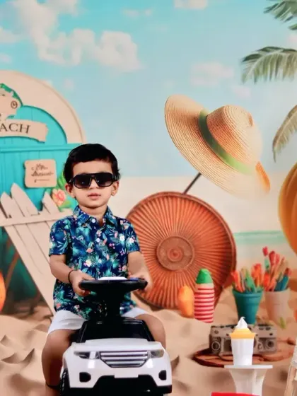 This cool toddler is ready for the beach, posing with a toy car and sunglasses in our sunny, sandy setup.