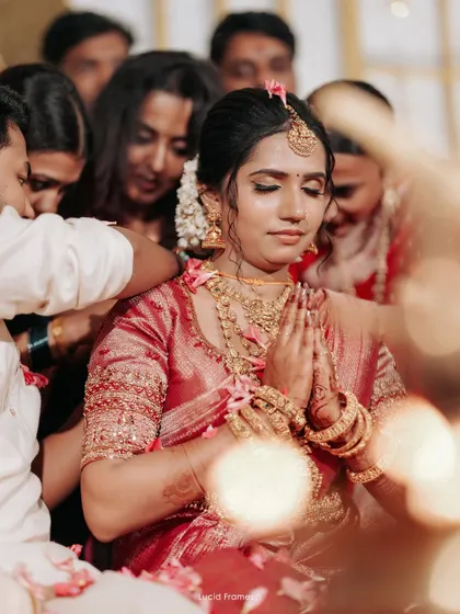 The bride in a moment of prayer, surrounded by the hands of her family, a powerful and emotional image.