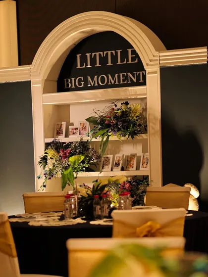A "Little Big Moment" display shelf, where the family could share treasured photos. We decorated the shelves with floral arrangements, creating a personal and heartwarming focal point for the event.