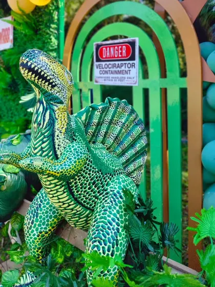 A close-up of a Spinosaurus model and a 'Velociraptor Containment' sign, adding a touch of Jurassic Park authenticity.