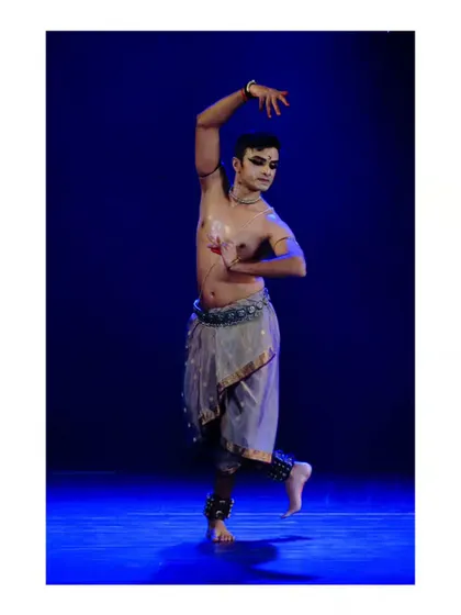 A graceful pose from a solo recital, showcasing the intricate details of the costume and the precision of the hand gestures, or 'mudras'.