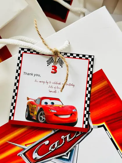 A close-up of the personalized tag for the "Cars" themed birthday favours, featuring Lightning McQueen and a sweet thank you message.