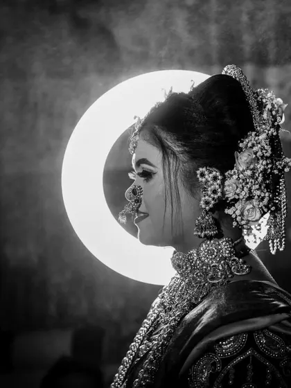 A dramatic black and white bridal profile, using a ring light to create a striking halo effect and highlight her ornate jewelry.