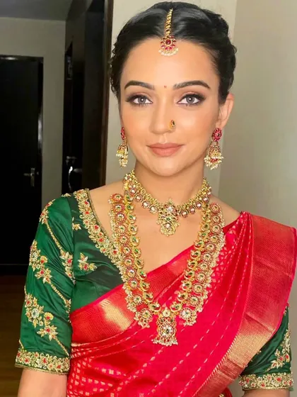 A classic red and green bridal combination. The makeup features a clean, sharp wing and a beautiful red lip, creating a timeless look for her wedding day.