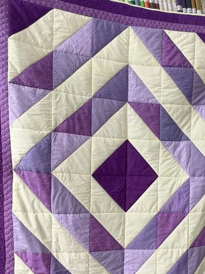 A close-up of a geometric quilt, showing the simple "stitch in the ditch" and straight-line quilting that accentuates the pattern.