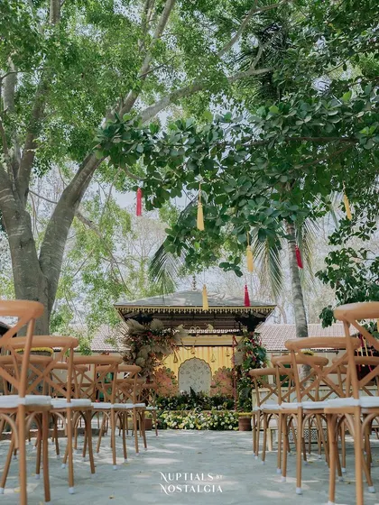 The guest seating area for the Haldi ceremony, with rustic cross-back chairs leading up to the beautifully decorated mandap.