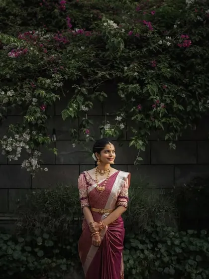 A simple, elegant portrait of the bride against a wall of flowers. Her calm demeanor and the natural beauty of the setting create a serene and timeless image.