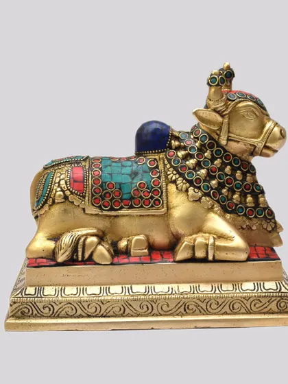 This brass Nandi, the sacred bull and vehicle of Lord Shiva, is adorned with colorful stonework. As the gatekeeper of Kailash, a Nandi statue is a symbol of devotion, faith, and protection, often placed facing the main deity in a home temple.