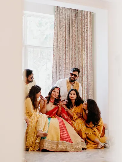 A candid portrait of the bride with her family, framed beautifully by a window during a quiet moment at the Haldi.