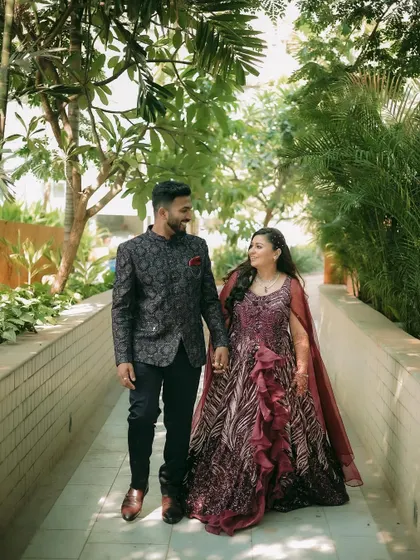 A full-length portrait of the couple walking down a tree-lined path, looking happy and in love.