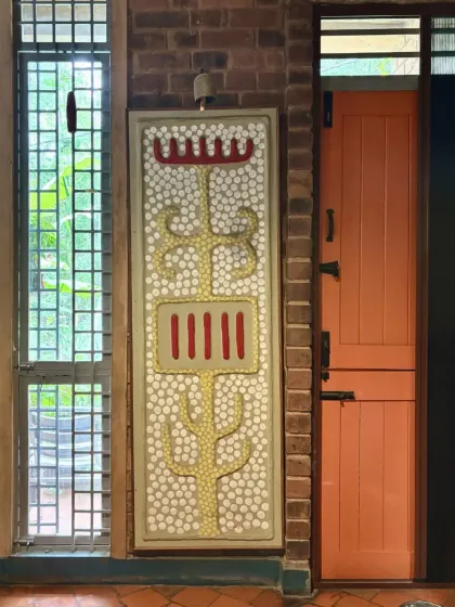 A decorative panel featuring a traditional motif, made with inlaid pebbles and colored plaster. This detail, placed next to a brightly painted door, shows our love for combining different textures, crafts, and colors.
