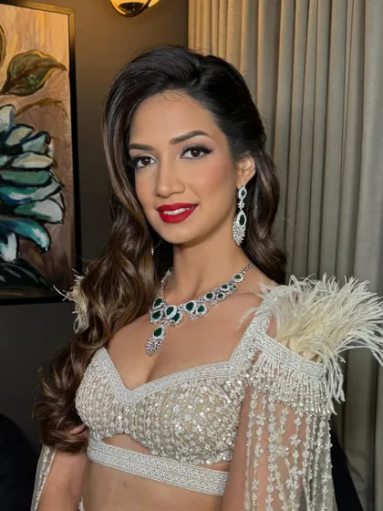 A smiling portrait of the bride, looking absolutely stunning with her glamorous waves and feathered outfit.