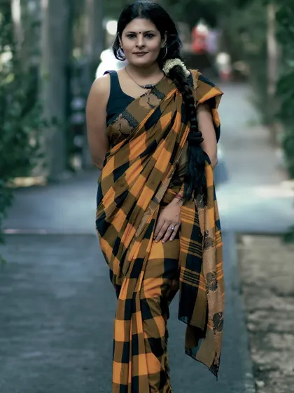 A full-length shot of the checkered saree, showing how it drapes and moves. The traditional braid adds a classic touch to the overall look.