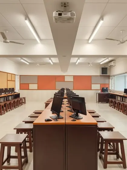 The computer lab is equipped with modern IT infrastructure in a clean, organized layout. The design ensures a comfortable and functional environment conducive to focused learning, with pin-up boards for displaying student work.