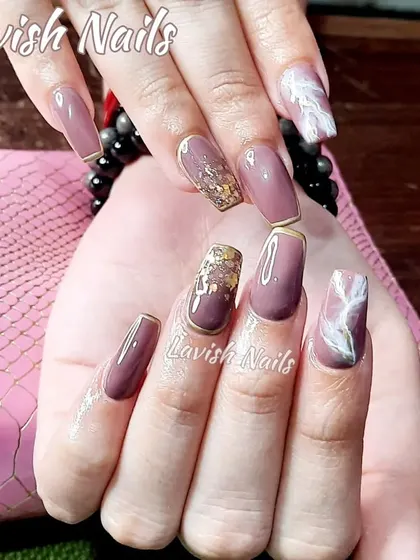 A sophisticated set with mauve polish, gold foil accents, and a white marble effect on accent nails, all framed with a delicate gold line.