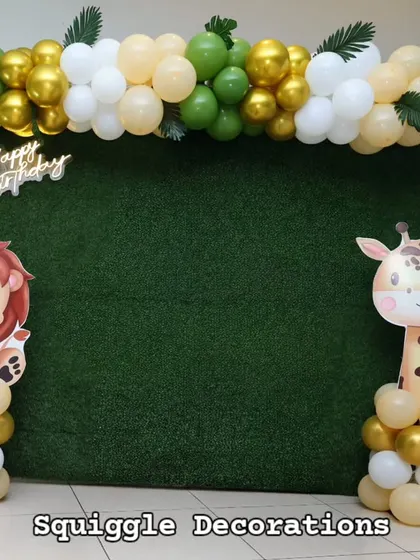 A clean and modern jungle theme photo booth with a grass wall, animal cutouts, and a simple balloon garland.