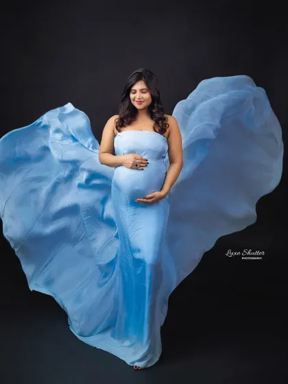 The flowing fabric of this light blue gown creates the shape of a heart, a beautiful symbol for a maternity photoshoot. It’s a simple yet powerful creative touch.