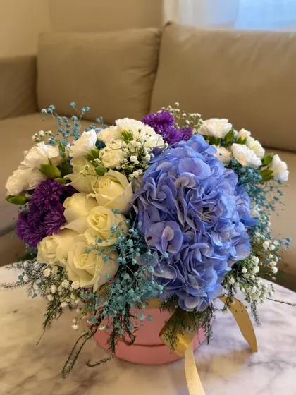 A closer look at the floral base for one of my hot air balloon gifts. This one features a stunning blue hydrangea surrounded by white and purple carnations and delicate baby's breath in a soft pink box.